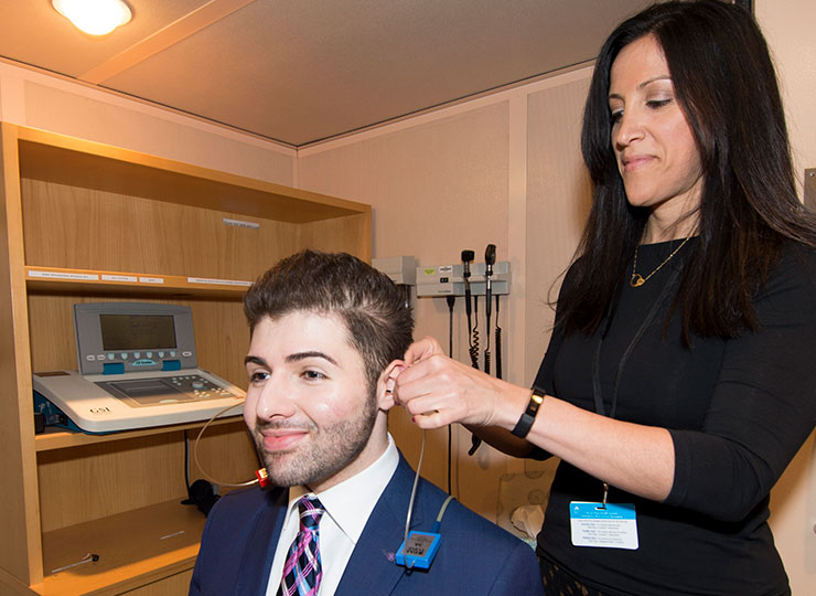 Photo of Female doctor putting hearing device on male patient