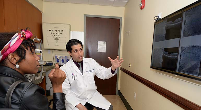 Dr. Avnish Deobhakta, NYEE retina specialist, discussing test results with a female patient