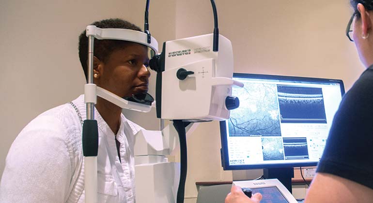 Female patient having an eye scan with medical imaging technician